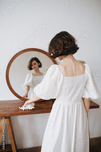 Mirror portrait of a sensual shy woman in a white dress.