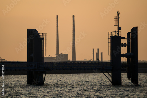 Beautiful telephoto view Poolbeg CCGT chimneys and Pigeon House Powers Station between wingwalls of St Michael pier ferry terminal in Dun Laoghaire harbor, Dublin, Ireland. Soft and selective focus