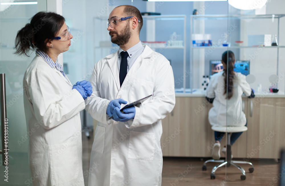 Fototapeta premium Scientist woman analyzing virus expertise with biologist researcher dicussing prevention treatment during clinical examination in microbiology hospital laboratory. Sickness investigation