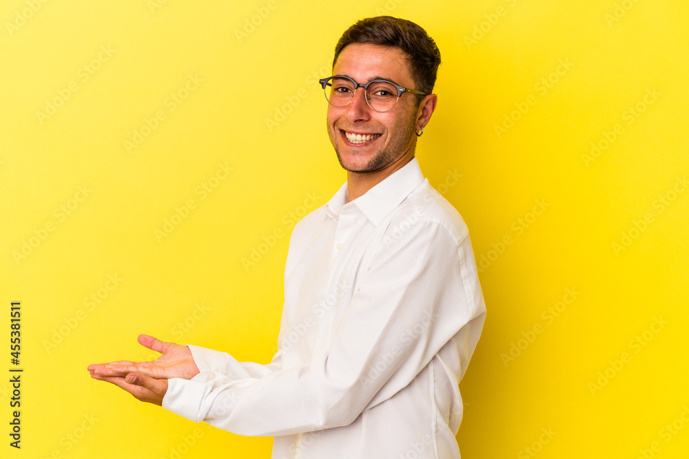Young caucasian man with tattoos isolated on yellow background holding a copy space on a palm. Young caucasian man with tattoos isolated on yellow background holding a copy space on a palm.