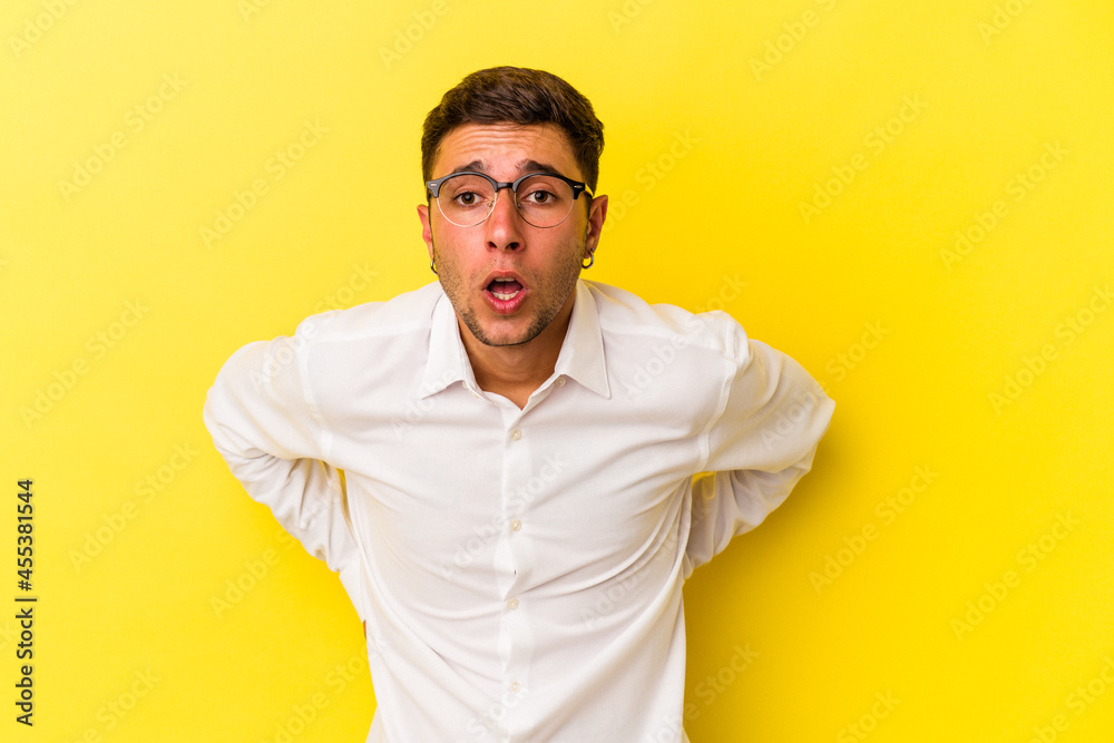 Young caucasian man with tattoos isolated on yellow background  being shocked because of something she has seen.
