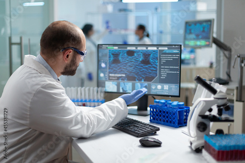 Specialist biologist researcher man analyzing virus expertise on computer discovering coronavirus vaccine. Biochemist doctor working in biochemistry hospital laboratory during clinical investigation