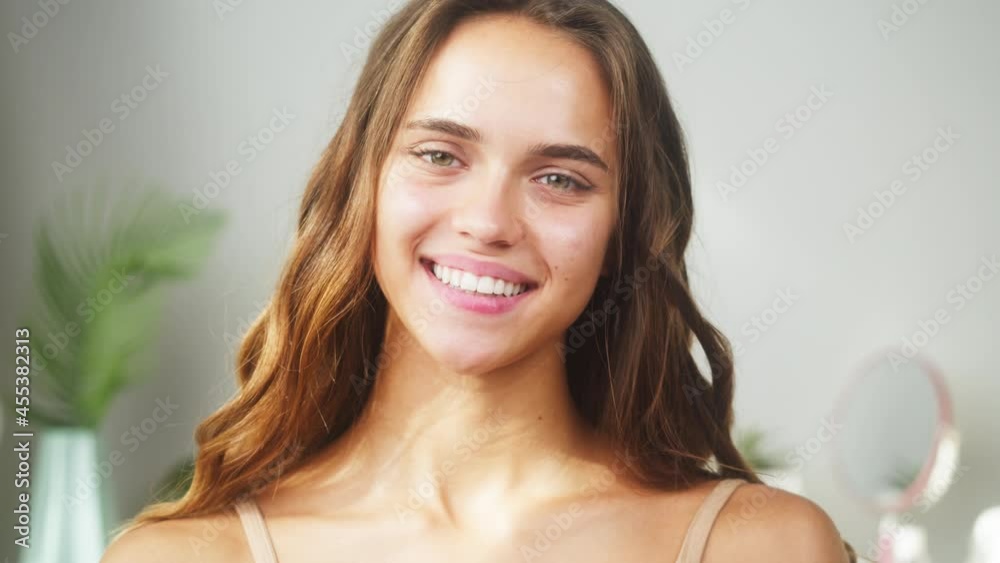 Happy woman smiling in bathroom or spa salon. Portrait of young female student with natural day make up, facial skincare concept. Attractive model with smooth skin looking in camera. 