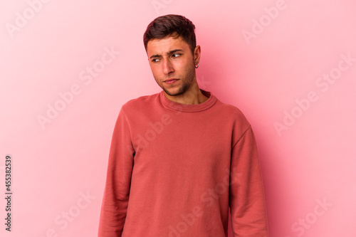 Young caucasian man with tattoos isolated on yellow background shrugs shoulders and open eyes confused.
