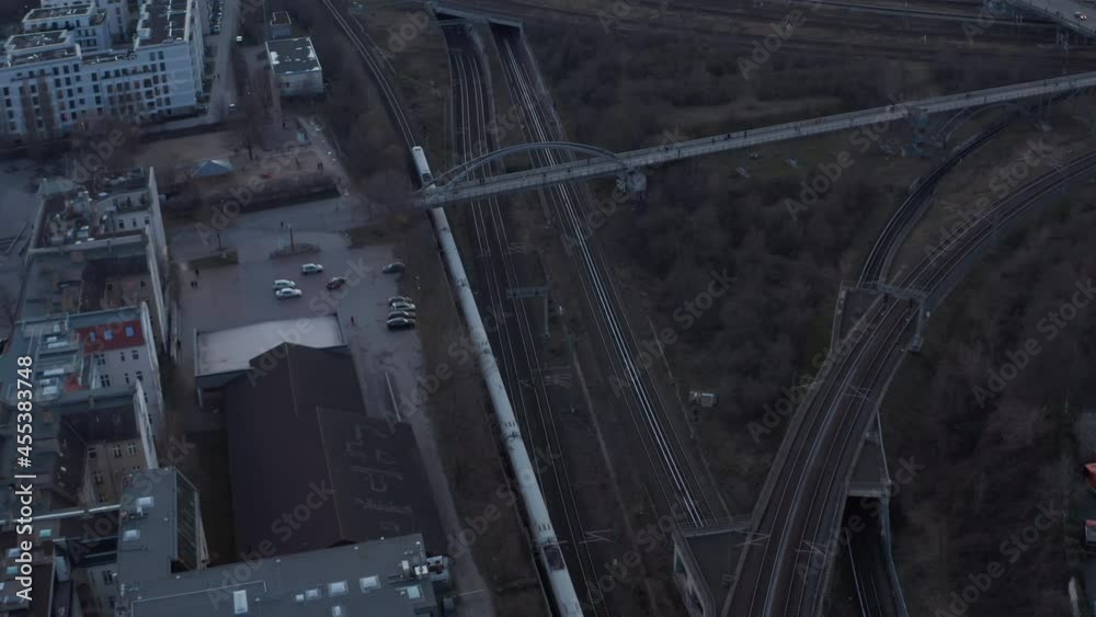 Aerial view of a passenger train passing by trees in Berlin, Germany surrounded by residential house during an early morning Aerial view of a passenger train passing by trees in Berlin, Germany surrounded by residential house during an early morning