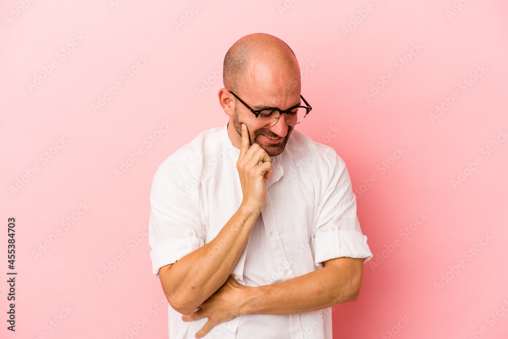 Young caucasian bald man isolated on pink background laughs happily and has fun keeping hands on stomach. Young caucasian bald man isolated on pink background laughs happily and has fun keeping hands on stomach.