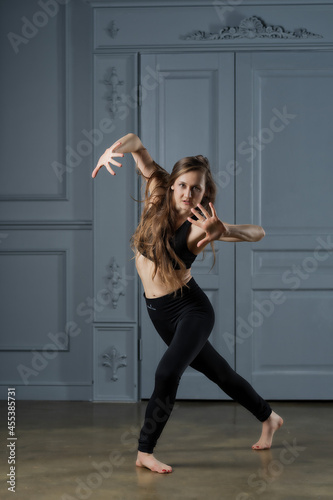 a girl with long hair in a black dance track rehearsing a dance in a ballet studio