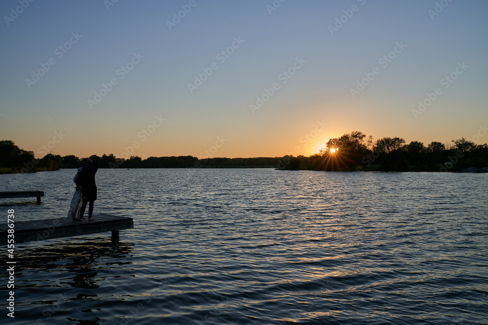 Scenic View of Illinois Dock Lake Sunset with Mother and Daughter Standing on the Dock Viewing the Sunset 