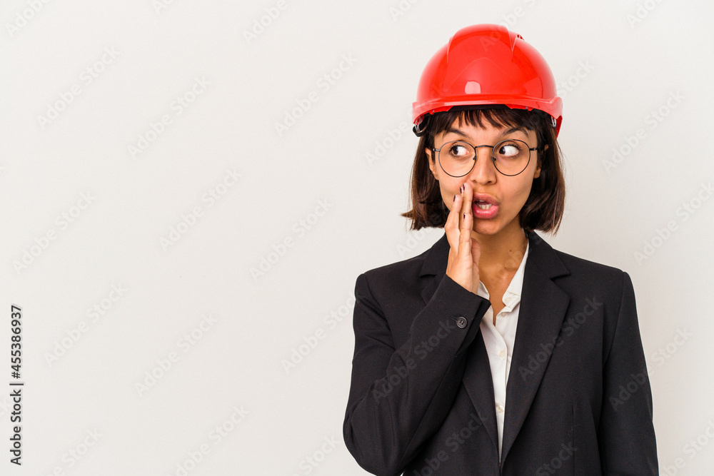 Young architect woman with red helmet isolated on white background is saying a secret hot braking news and looking aside Young architect woman with red helmet isolated on white background is saying a secret hot braking news and looking aside