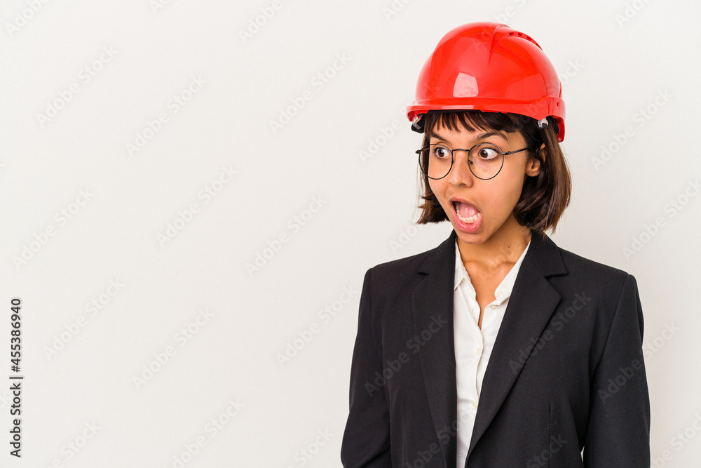 Young architect woman with red helmet isolated on white background being shocked because of something she has seen. Young architect woman with red helmet isolated on white background being shocked because of something she has seen.
