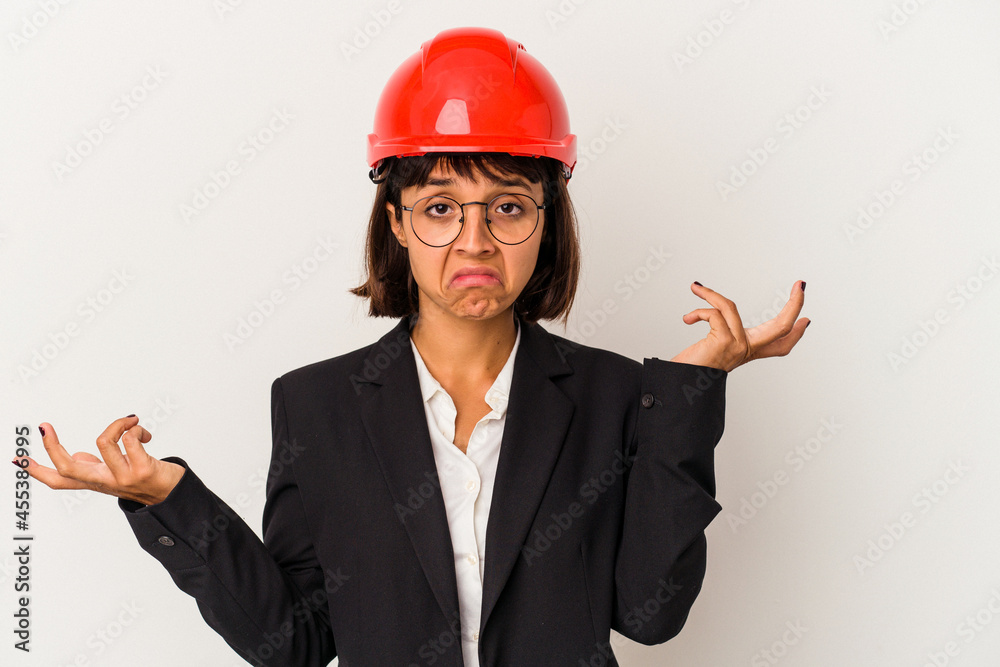 Young architect woman with red helmet isolated on white background doubting and shrugging shoulders in questioning gesture. Young architect woman with red helmet isolated on white background doubting and shrugging shoulders in questioning gesture.