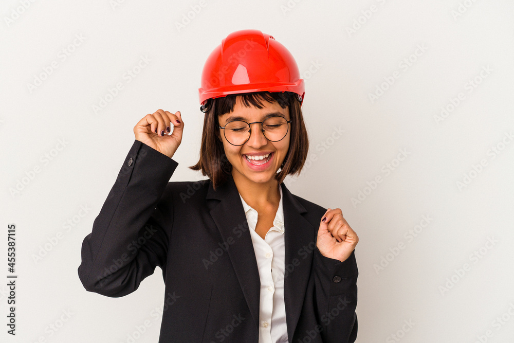 Young architect woman with red helmet isolated on white background celebrating a special day, jumps and raise arms with energy. Young architect woman with red helmet isolated on white background celebrating a special day, jumps and raise arms with energy.