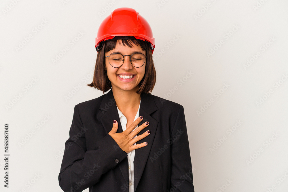 Young architect woman with red helmet isolated on white background laughs out loudly keeping hand on chest. Young architect woman with red helmet isolated on white background laughs out loudly keeping hand on chest.