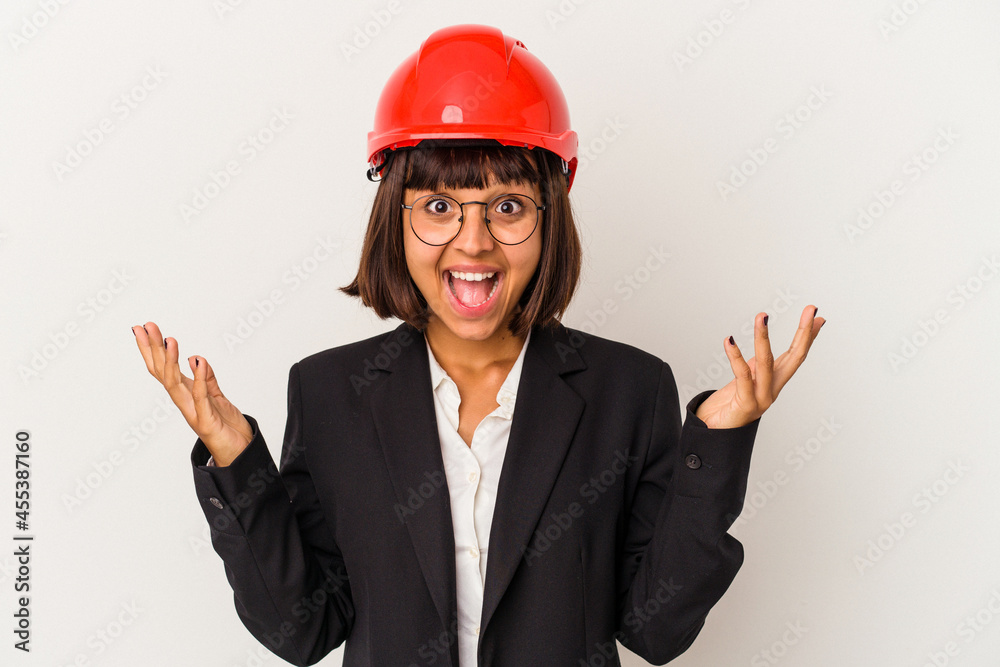 Young architect woman with red helmet isolated on white background receiving a pleasant surprise, excited and raising hands. Young architect woman with red helmet isolated on white background receiving a pleasant surprise, excited and raising hands.