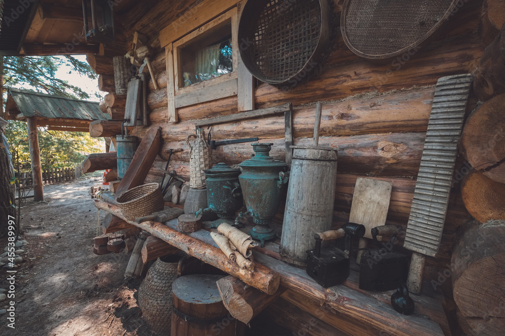 Retro houseware on a wooden bench near wooden wall. Antique household items of peasant.