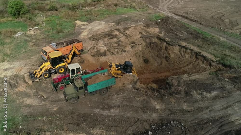 Drone view of a massive pit and heavy machinery removing dirt out of it Drone view of a massive pit and heavy machinery removing dirt out of it