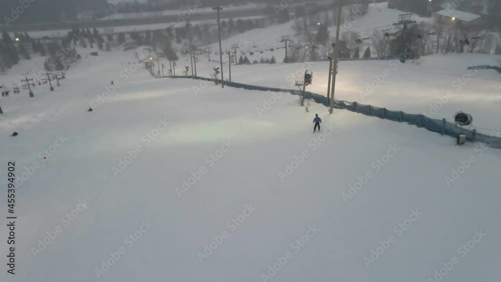 People going down hill skiing and snowboarding on a ski resort in Minnesota during a winter evening