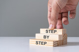 Hand arrange wood block in staircase for step by step guide or career path