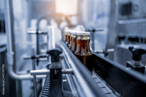 Factory interior of beverage  Production line of manufacturing and packaging juice products  Close up  Glass bottles with screw caps standing on a conveyor belt.