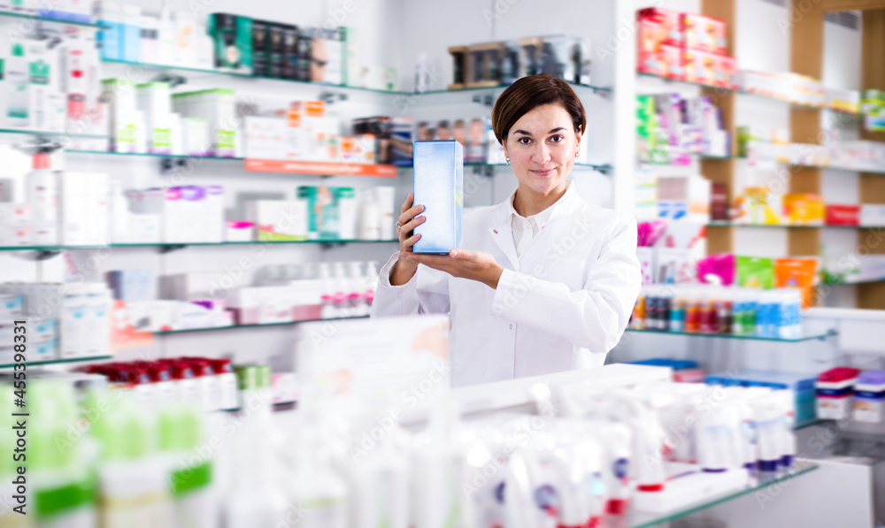 Adult female pharmacist offering products of body care in pharmacy