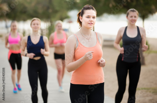 Fototapeta Naklejka Na Ścianę i Meble -  Positive girls running during outdoor workout on city seafront.
