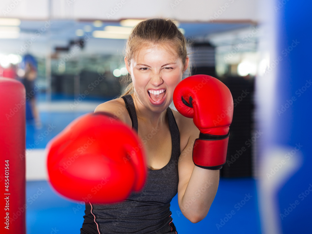 Portrait of young woman in red boxing gloves training in fitness center