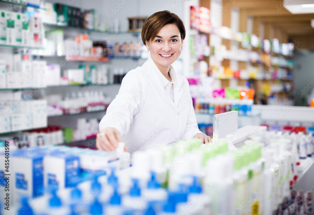 Smiling pharmacist organizing assortment of care products in pharmacy