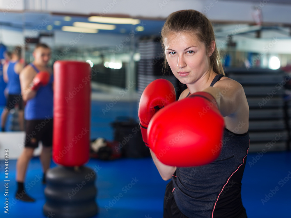 Portrait of young positive female who is boxing in fitness center