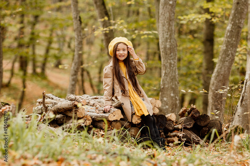 a little brunette Asian girl in autumn clothes walks in the autumn forest near a stream. High quality photo