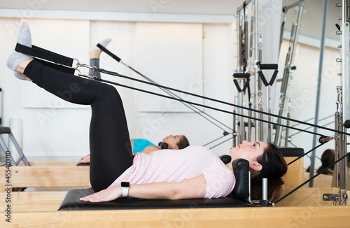 Woman exercising torson rotation at gym using pilates reformer beds