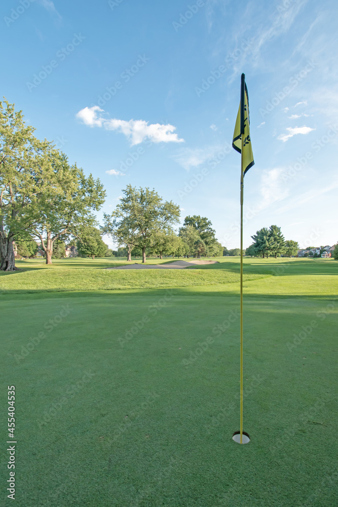 Obraz premium A flag points skyward on a golf course green in late afternoon.