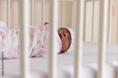 Newborn baby girl wrapped up and sleeping in crib