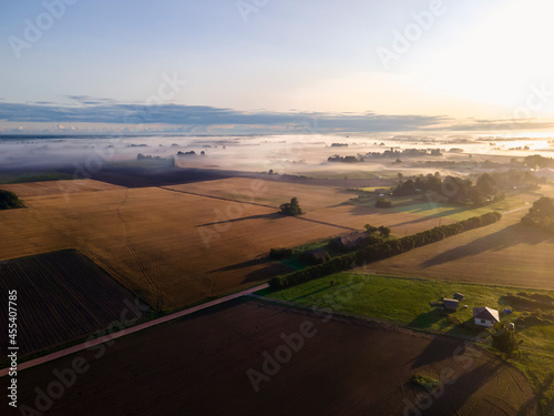 Flying with drone above fields early in the morning while sun is rising and nature is waking up