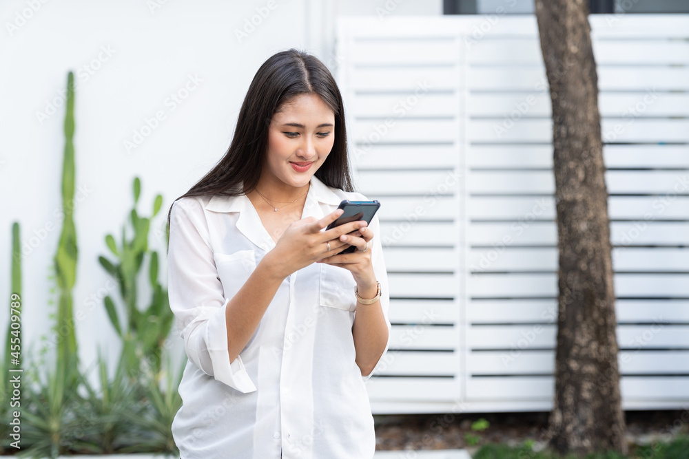 Asian young businesswoman in wear casual saying hi to the mobile camera during using smart phone video call while standing near the business office. Asian young businesswoman in wear casual saying hi to the mobile camera during using smart phone video call while standing near the business office.