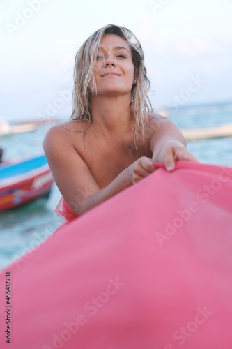 Beautiful young woman on the beach with red material