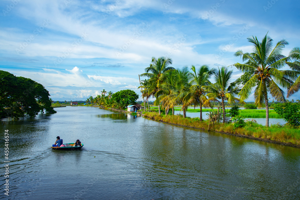 Fisher man paddling a coracle boat (Kotta vanchi) at Kadamakkudy lake during day time, Kerala backwaters photography Fisher man paddling a coracle boat (Kotta vanchi) at Kadamakkudy lake during day time, Kerala backwaters photography