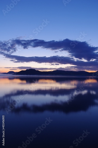 夜明けの空を湖面に反射する湖。日本の北海道の屈斜路湖で。