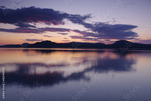 夜明けの空を湖面に反射する湖。日本の北海道の屈斜路湖で。 © Masa Tsuchiya