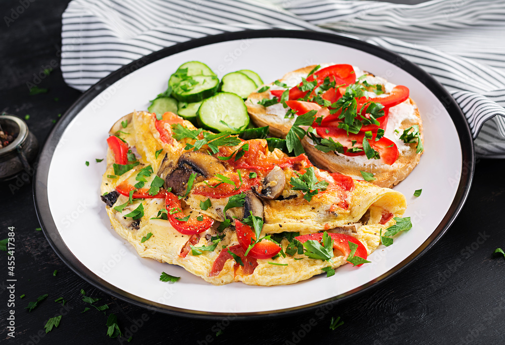 Omelette with mushrooms, paprika, tomatoes and sandwich with cream cheese on white plate. Frittata - italian omelet. Omelette with mushrooms, paprika, tomatoes and sandwich with cream cheese on white plate. Frittata - italian omelet.