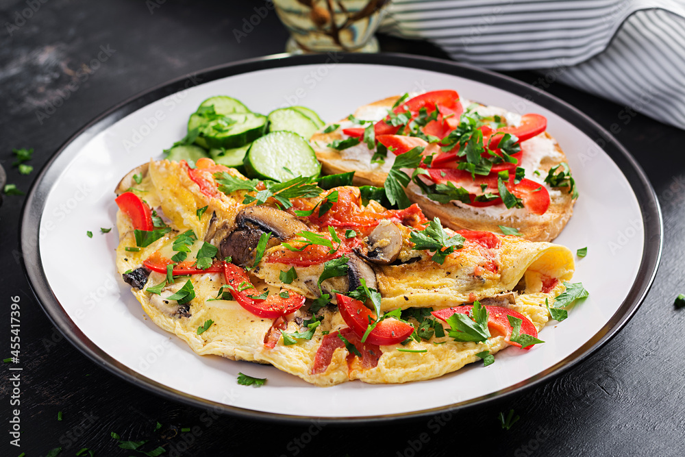 Omelette with mushrooms, paprika, tomatoes and sandwich with cream cheese on white plate. Frittata - italian omelet. Omelette with mushrooms, paprika, tomatoes and sandwich with cream cheese on white plate. Frittata - italian omelet.