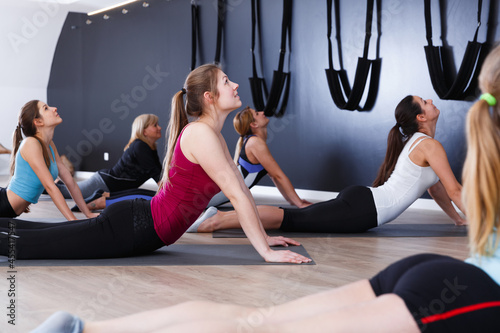 Smiling young women training yoga positions in modern yoga studio