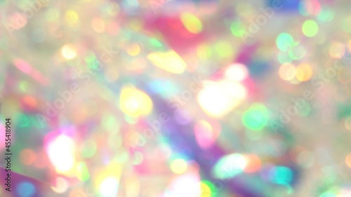 Light through a prism. Christmas holiday texture and the background. Holographic pastel gradient. Blurry neon lights. New Year's tinsel