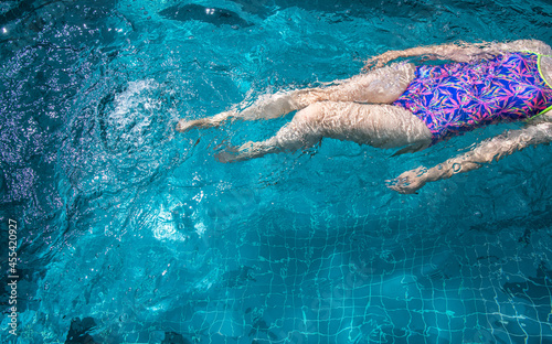 A woman is swimming in the pool on a sunny day