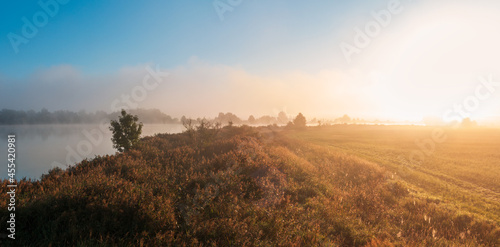 Panoramic view to pond with misty fog and meadow. Amazing morning sunrise, late summer Czech landscape