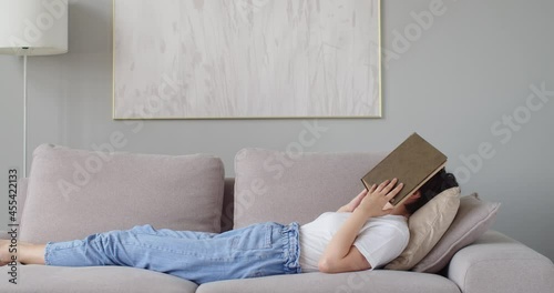 Wallpaper Mural Sleepy woman reading paper book relaxing at home after hard work. Girl in jeans lying on sofa exhausted trying to sleep. Slow motion copy space text. Working conditions self-isolation leisure time Torontodigital.ca