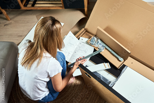 Woman reading manual instruction to assemble furniture photo