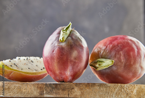 Peruvian apple cactus fruits whole and cut on wooden stand on gray board. Scientific name Cereus repandus photo