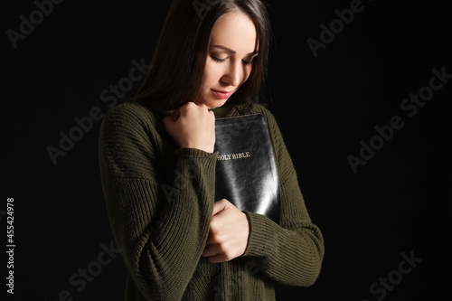 Praying young woman on dark...