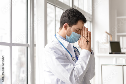 Religious doctor praying in...