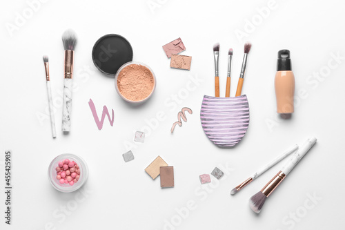 Makeup brushes with decorative cosmetics on white background